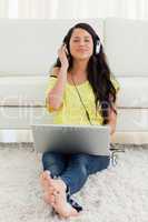Pretty Latin enjoying music on a laptop