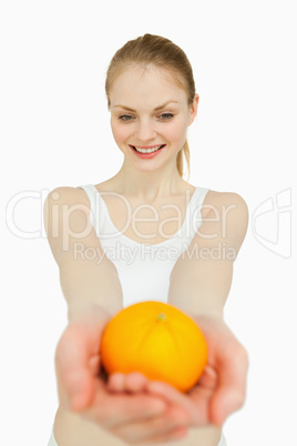 Woman presenting a tangerine while looking at it