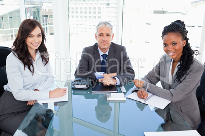 Mature director sitting at the desk and accompanied by two busin