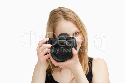 Fair-haired woman aiming with a camera