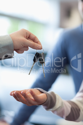 Salesman holding keys over the hand of a customer
