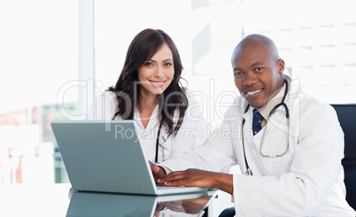 Smiling medical staff working in front of a laptop while sitting