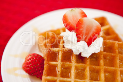 Half cut strawberry and whipped cream on a white plate