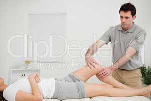 Serious doctor holding the knee of a woman