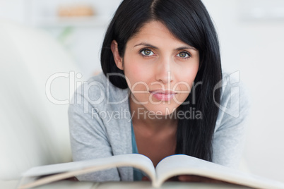 Woman holding a book while resting on a sofa