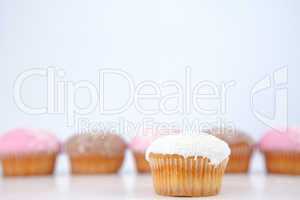 Muffin placed in front of a line of muffin with icing sugar