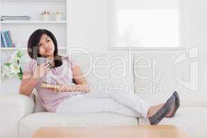 Woman thinking while holding a mug and a book