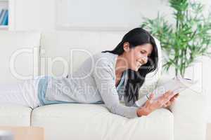 Woman reading a magazine as she lays on a couch
