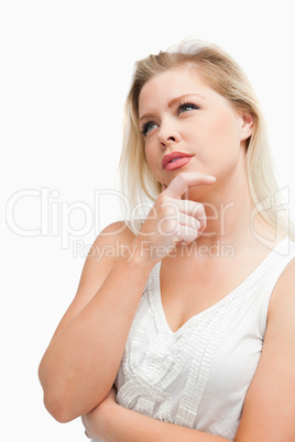 Thoughtful blonde woman looking up while standing