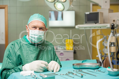 Surgeon sitting next to a table full of a surgical tools