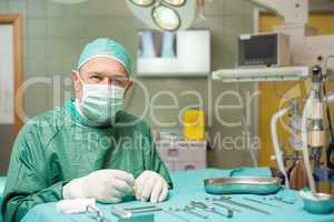 Surgeon sitting next to a table full of a surgical tools