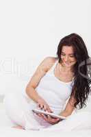 Smiling woman using a tablet pc on her bed