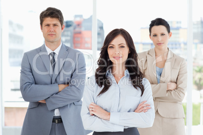 Three business people crossing their arms in front of a bright w