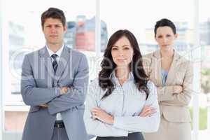 Three business people crossing their arms in front of a bright w