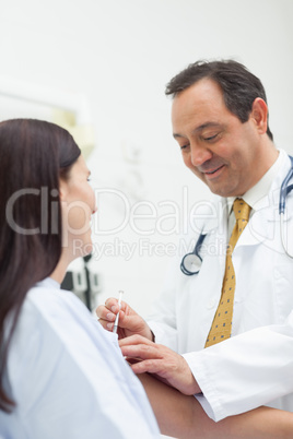 Smiling doctor doing an injection to a patient