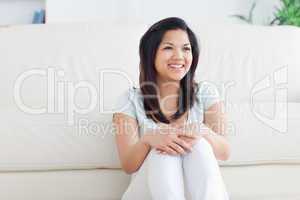 Woman smiles as she sits in front of a couch on the floor