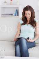 Woman sitting on a sofa while looking at a magazine