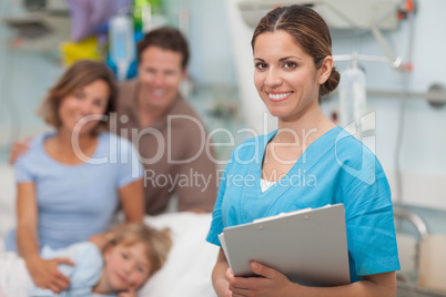 Nurse holding a clipboard next to a family
