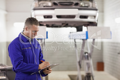 Mechanic holding a clipboard while looking at it Mechanic holding a clipboard while looking at it