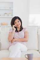 Smiling woman phoning while sitting on a couch