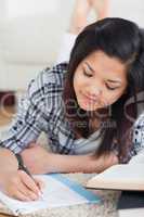 Woman lying on the floor while writing on a notebook