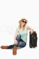 Blonde-haired woman sitting near a suitcase
