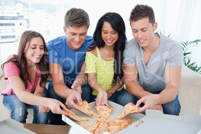friends grabbing some pizza as they look at the box