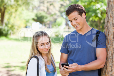 Close-up of a student showing his smartphone screen to a girl