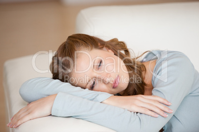 Woman lying on a sofa crossing her arms looking down