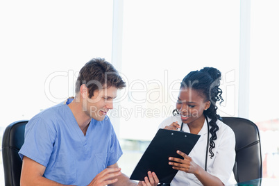 Two nurses working on a professional clipboard in a bright room