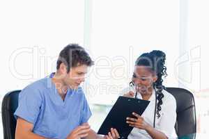 Two nurses working on a professional clipboard in a bright room