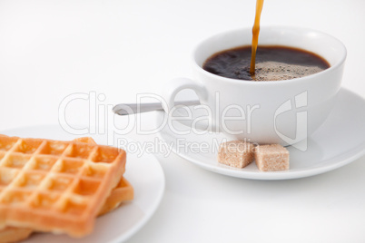 Waffles sugar and a cup of coffee on white plate
