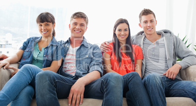 Two couples sit on the couch together looking into the couch