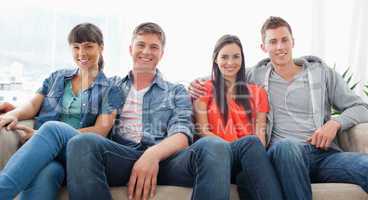 Two couples sit on the couch together looking into the couch