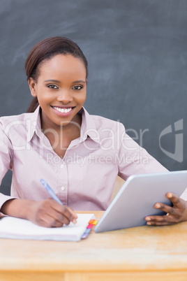 Teacher writing while using a tablet computer