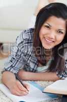 Smiling woman on the floor writing on a notebook