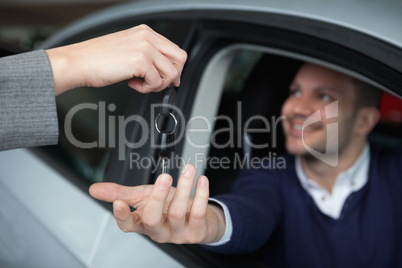 Man receiving car keys while sitting in his car