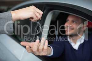Man receiving car keys while sitting in his car