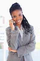 Young smiling employee standing upright and talking on a phone w