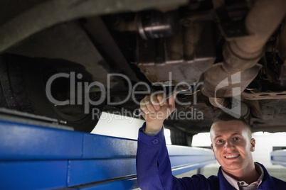 Smiling mechanic looking at camera while repairing