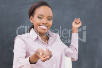 Black teacher showing the blackboard while smiling
