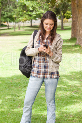 Young student standing while using a smartphone