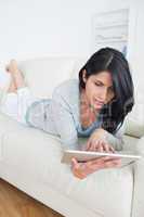 Woman playing with a tactile tablet while laying on a couch