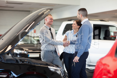 Man shaking hand of a car dealer in front of a car