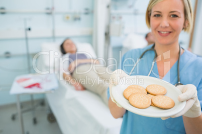Smiling nurse holding a plate of biscuits