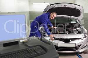 Mechanic leaning on a car next to a computer