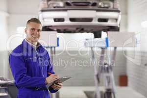 Smiling mechanic holding a clipboard while looking at camera