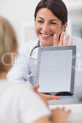 Smiling doctor showing a tablet computer to a child