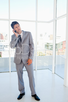 Businessman making a call while looking upwards