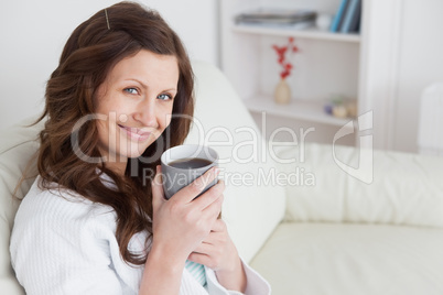 Woman sitting on a sofa holding a mug of cofee
